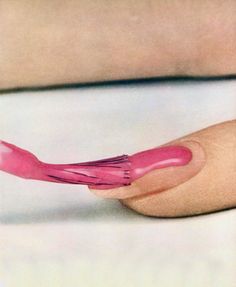 a woman's hand holding a pink toothbrush with long, pointed tips on it