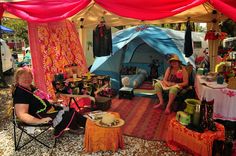 two women sitting in chairs under a tent with red drapes on the outside and inside