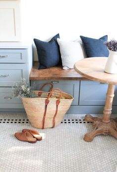 a basket sitting on top of a floor next to a wooden table and bench in a room