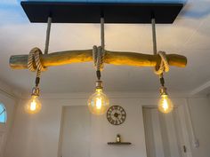 three light bulbs are hanging from a beam made out of wood and rope on the ceiling