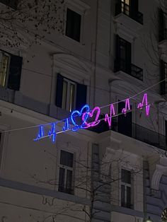 a neon sign that is on the side of a building in front of a tree