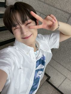 a young man making the v sign with his hand while standing in front of stairs