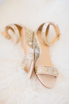 a pair of high heeled shoes sitting on top of a white fur covered floor