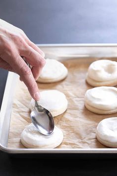 a person is spooning some food out of a baking pan with doughnuts on it