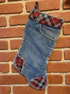 an old pair of jean shorts hanging on a brick wall with a plaid tie around it