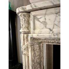 a white marble fireplace surround with carvings on it