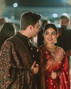 a man and woman standing next to each other in front of a group of people