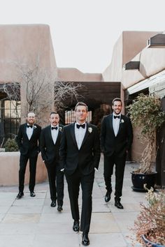 a group of men in tuxedos walking down a sidewalk