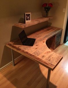 a laptop computer sitting on top of a wooden desk next to a shelf filled with pictures