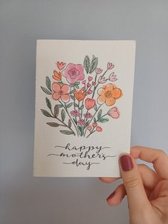 a hand holding up a card with flowers on it that says happy mother's day