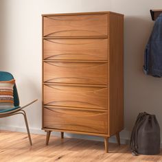 a wooden chest of drawers next to a blue chair