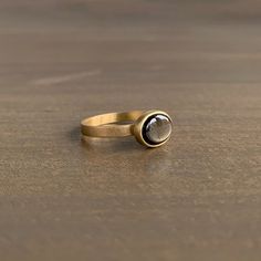 a close up of a ring on a wooden surface with a stone in the middle