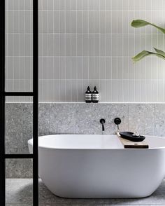 a white bath tub sitting next to a green plant