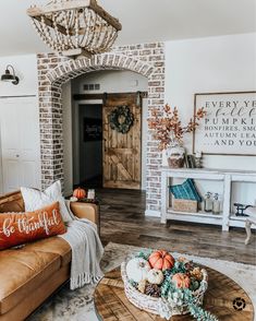 the living room is decorated for fall with pumpkins and greenery on the coffee table