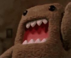 a brown stuffed animal with its mouth open and teeth wide open in front of the camera