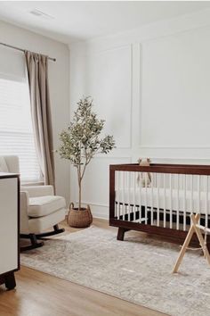 a baby's room with a crib, rocking chair, and tree in the corner