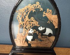 two panda bears are sitting on the ground under a glass dome with bamboo trees in it