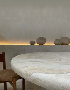 a table and two chairs in a room with white marble walls, round light fixture on the wall