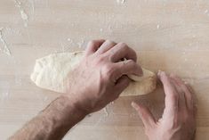 a person kneading dough on top of a wooden table