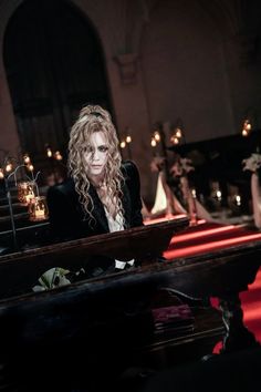 a woman sitting at a piano in front of candles