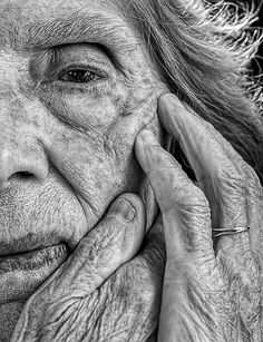 black and white photograph of an elderly woman holding her hands to her face with both hands