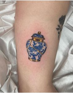 a small blue and white vase tattoo on the arm