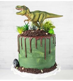 a dinosaur cake with green frosting and plants on top