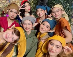 a group of young women in costumes posing for a photo with one woman's head wrapped around her neck