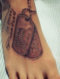 a foot tattoo with two tags on it