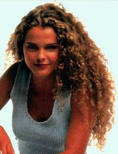 a woman with long curly hair holding a tennis racquet