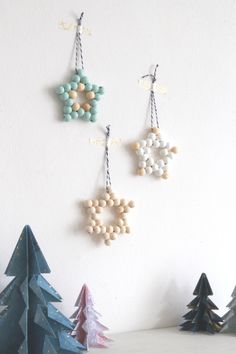 three wooden ornaments hanging on the wall next to christmas trees and snowflakes