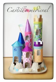 a group of little houses made out of toilet paper on a tray with toothbrushes in them