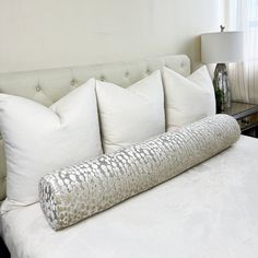 a bed with white pillows and silver sequins on it