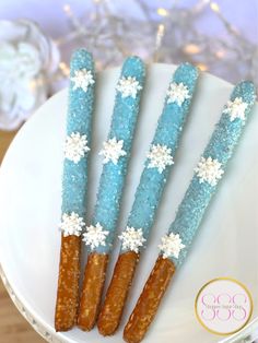 four blue and white snowflaked sticks on a plate with some candy canes