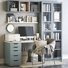 a computer desk sitting in front of a book shelf filled with books and other items