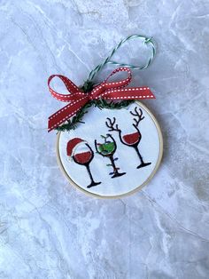 a cross stitch christmas ornament hanging on a marble surface with a red ribbon