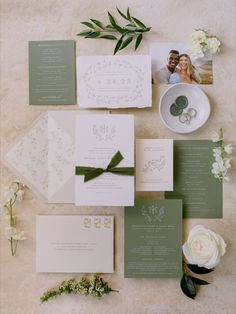 the wedding stationery is laid out with flowers and greenery