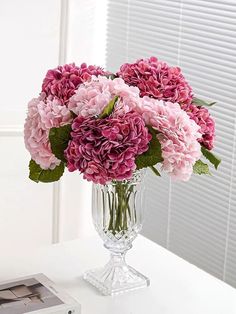 a vase filled with pink flowers on top of a white table