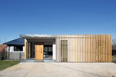 a modern house with wooden slats on the front and side walls, in an open area