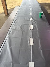 a long table covered in gray tarp with two cups sitting on top of it