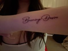 a woman's arm with the words burning desire written on it in cursive font