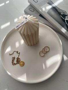 a white plate topped with jewelry and a cupcake on top of it next to a book