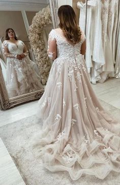 a woman standing in front of a mirror wearing a wedding dress