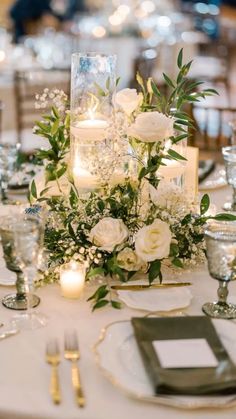 a table set with candles and flowers on top of it, surrounded by silverware