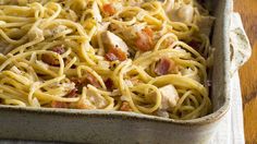 a pan filled with pasta and chicken on top of a wooden table