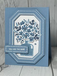 a blue and white card with an image of a vase filled with flowers on it