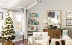 a living room filled with white furniture and a christmas tree in the middle of it