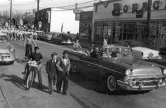 an old black and white photo of people walking down the street in front of cars