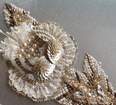 two brooches are sitting on top of a cloth covered pillow with beads and pearls