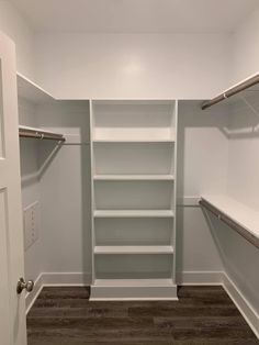 an empty walk in closet with white shelves